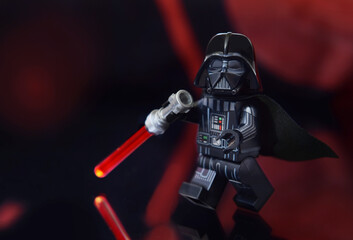 Naklejka premium Lego minifigure of Darth Vader from Star Wars with lightning sword is walking. Editorial illustrative image of toy from popular children construction