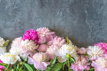 Happy mothers day or birthday greeting card template. Frame of white, pink and purple peony flowers on a gray background; copy space