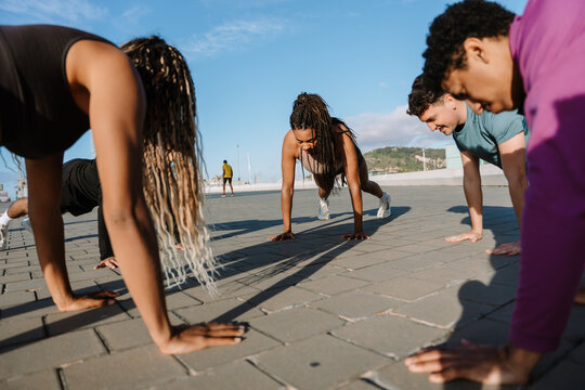 A group of five athletes in a circle stand in a push-up position