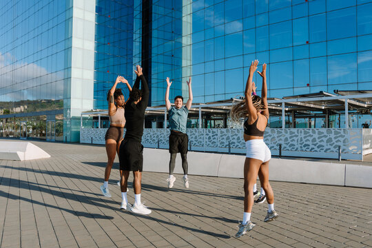A group of five athletes jumping in a circle with their arms raised