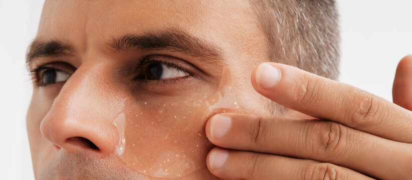 Detail shot of an under-eye hydrogel patch on male skin.