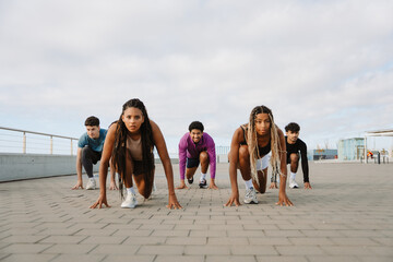 A group of five athletes stand in a starting position while the women in front of the men