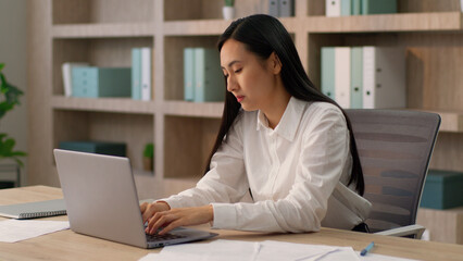 Unhealthy sick depressed sad Korean Asian businesswoman office worker Japanese manager secretary business woman female suffering headache pain tension migraine rubbing forehead problem deadline inside