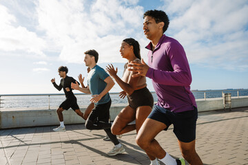 A group of five athletes running along the sea