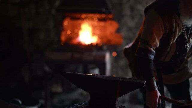 A Viking blacksmith with a white beard and braided hair works intently at a forge, hammering glowing metal on an anvil, with flames flickering in the background of a stone workshop cinematic slow