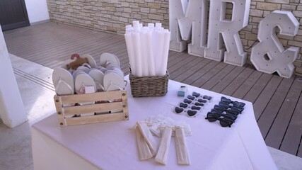 A beautiful setting showcases a table filled with guest items for a wedding. There are sunglasses, folded fans, and decorative letters in the background.