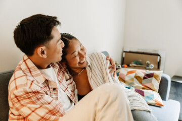 Man hugging woman while they sit on couch and laugh