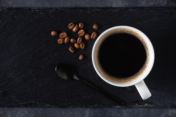 Black coffee in white porcelain cup on black chalkboard, top view copy space for text or design elements
