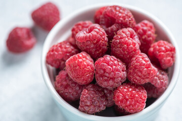 Group of fresh raspberries in a bowl. Juicy summer berries