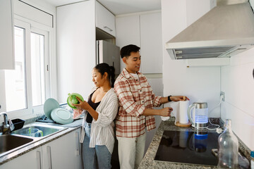 A man takes napkins and stands next to a woman who is wiping the juicer with a towel