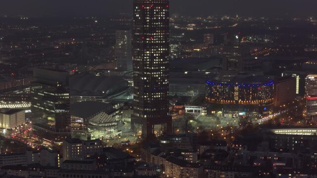 Nighttime aerial view of Frankfurt Fair area, featuring illuminated skyscrapers including Messeturm and bustling city street lights