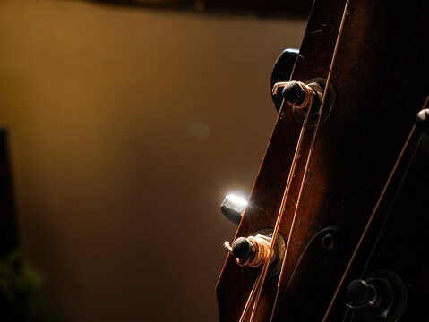 Guitar Headstock Side View: Wooden Neck with Tuning Pegs and Strings Close-up on Classic Acoustic Musical Instrument