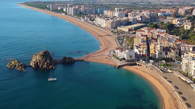 Magnificent aerial view showing the coastal town of blanes with its famous sa palomera rock, separating the bay from the long sandy beach, a popular summer destination in costa brava, spain