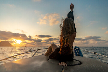 Woman boat sunset, young woman relaxing on front of boat enjoying golden ocean sunset, feeling freedom, copy space