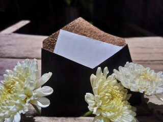 White Flowers with Prayer Beads and Elegant Envelope on Wooden Table &ndash; Natural Light 