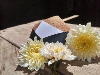 White Flowers with Prayer Beads and Elegant Envelope on Wooden Table &ndash; Natural Light 