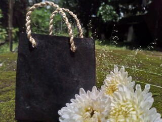 Black Shopping Bag with White Flowers on Moss Background &ndash; Natural Decorative Still Life