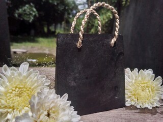 Black Shopping Bag with White Flowers on Moss Background &ndash; Natural Decorative Still Life