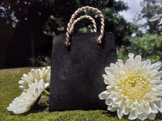 Black Shopping Bag with White Flowers on Moss Background &ndash; Natural Decorative Still Life