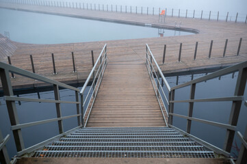Fototapeta premium Foggy Pier with Metal Railings Over Water