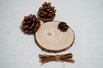 Natural wooden elements arrangement featuring pine cones, wooden slice, and bundled twigs on textured background for rustic decor or crafting projects