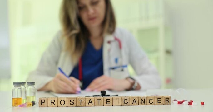 Wooden blocks spell words Prostate Cancer near pills and stethoscope while woman doctor works. Female doctor writes notes planning screening