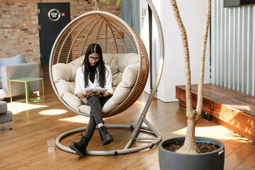 Female worker reading a folder and holding a pencil while sitting in a cocoon chair