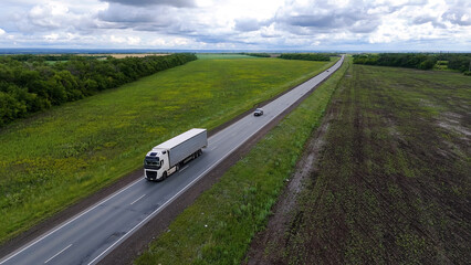 trucks are driving on the highway, surrounded by summer green fields