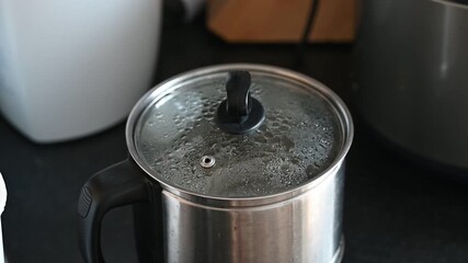 Electric kettle lid closing while water is boiling, creating a sharp mechanical lid click, loud water gurgling, and steam hissing sound.
