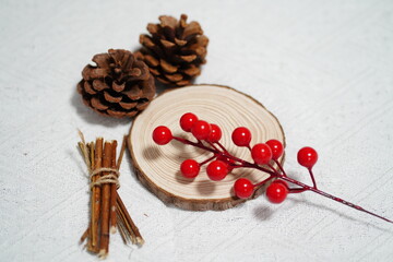 Natural Decorative Elements Featuring Pine Cones, Red Berries, Wooden Slice, and Sticks on a Textured Background for Seasonal Crafts and Home Decor