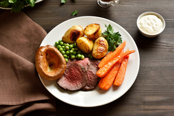Sunday Roast with roasted beef, carrots, crispy potato, green pea and yorkshire pudding.