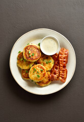 Potato pancakes made from mashed potato and green onion served with crispy rosted bacon and sauce