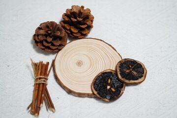Natural rustic decor elements featuring wood slice, pine cones, dried citrus slices, and twigs on textured white background for seasonal design projects