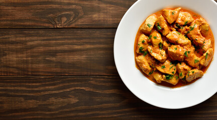  Indian dish chicken tikka masala on plate on wooden background