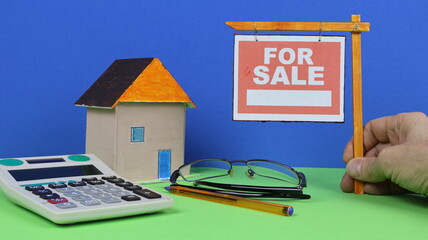 Primo piano di un cartello "in vendita" su un palo nel cortile anteriore di una casa, immagine composita in studio con sfondo blu e verde.