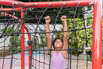 Happy child climbing playground rope structure outdoors