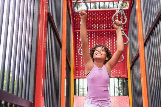 Happy girl playing on monkey bars at playground