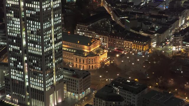 Stunning aerial footage showing illuminated Alte Oper concert hall and modern skyscrapers in financial district of Frankfurt, Germany at night
