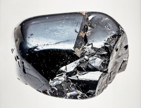 A single piece of raw obsidian with glassy luster and sharp conchoidal fractures, isolated on white.