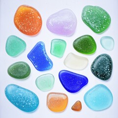 A collection of colorful sea glass pieces in various shapes and pastel colors, isolated on pristine white background.