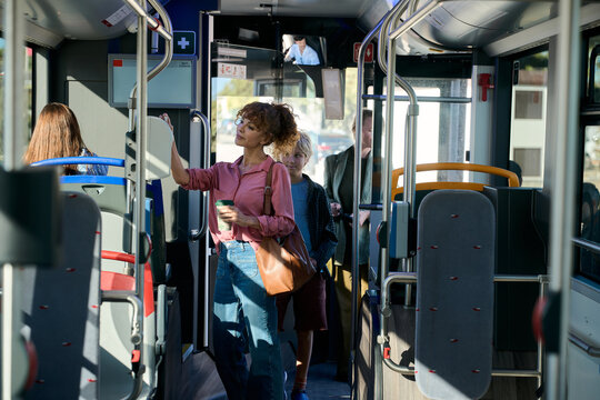 Woman traveling on public bus holding coffee cup