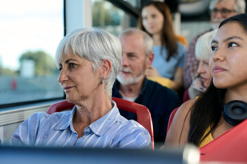 Diverse passengers traveling by bus looking out window