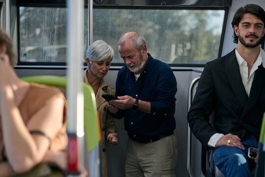 Senior couple using smartphone on public transport