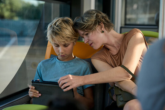Mother and son using tablet on bus