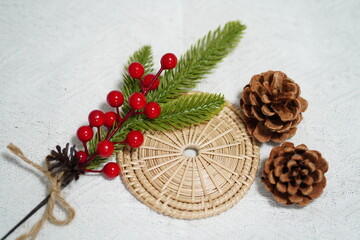 Decorative winter arrangement featuring pine cones, holly berries, and greenery on a textured...