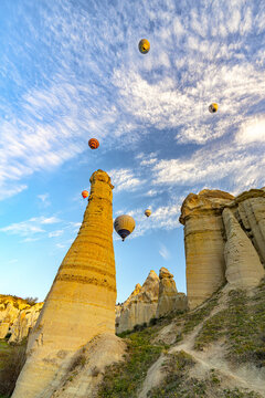 View of fairy chimneys pierce the sky as colorful hot air balloons float serenely above the unique landscape, Cappadocia, Love valley, Cappadocia, Turkey.