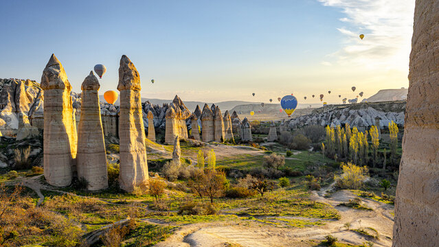 Love valley, Turkey - 20 April 2025: View of the fairy chimneys piercing the sky, as hot air balloons float amidst the golden light of dawn.