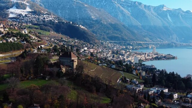 Aerial view of the historic Chatelard Castle standing proudly amidst rolling hills and vineyards, overlooking the serene lake, Montreux, Vaud, Switzerland.
