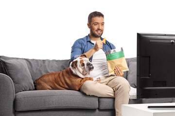 Man eating crisps on a sofa with a bulldog and watching tv