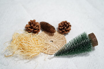 Close-Up Arrangement of Pine Cones, Miniature Evergreen Tree, Natural Elements, and Craft Materials on Textured Background for Seasonal Decor